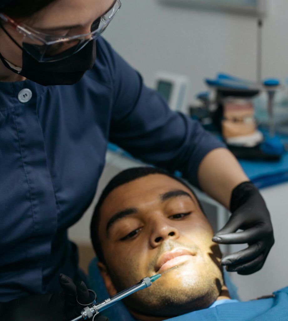 Dentista aplicando anestesia em paciente deitado durante atendimento odontológico.