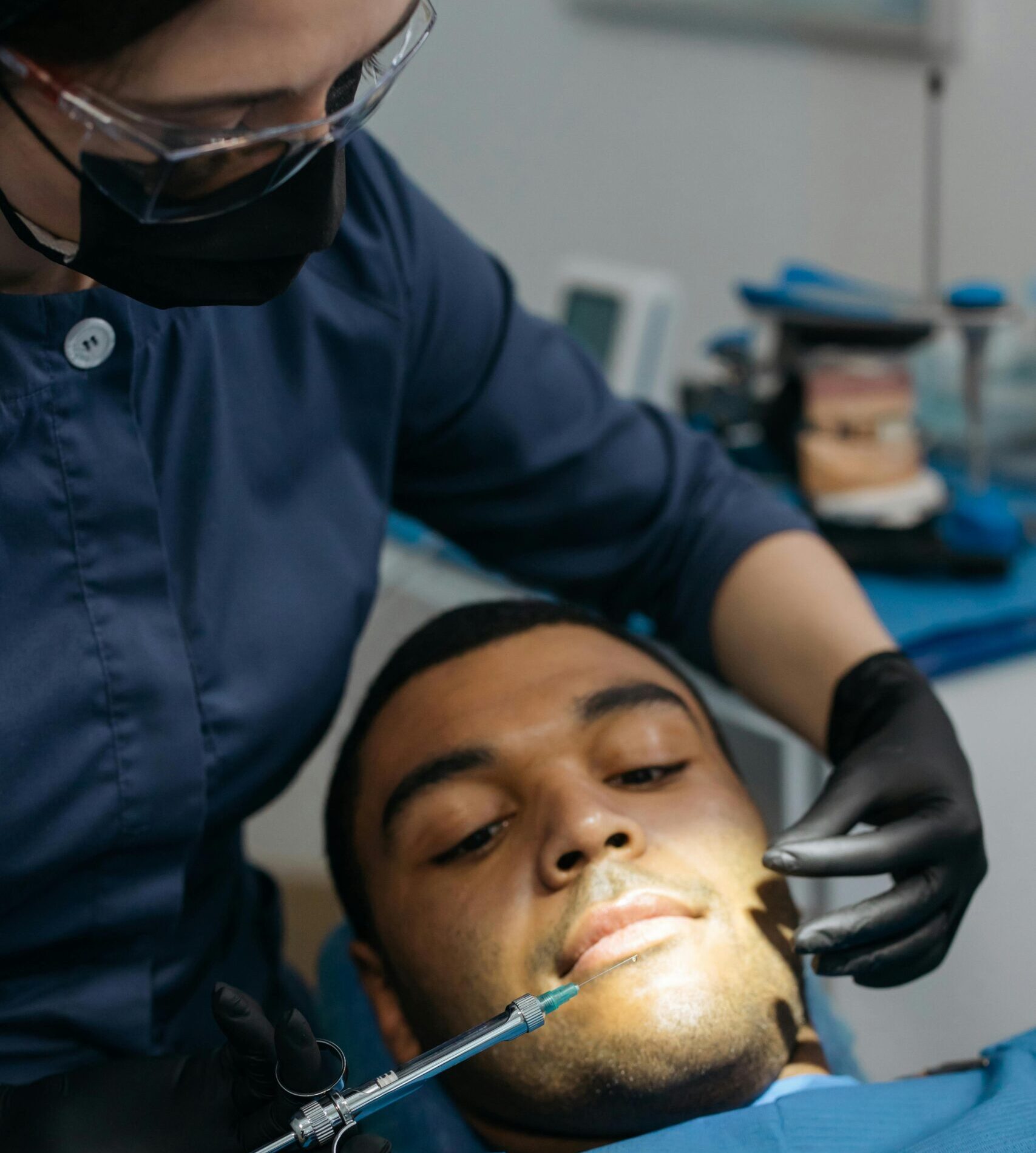 Dentista aplicando anestesia em paciente deitado durante atendimento odontológico.